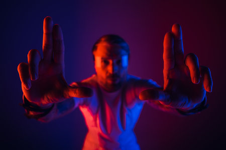 A man in a white shirt stands in a studio setting wearing smart glasses and holding up two fingers.の写真素材