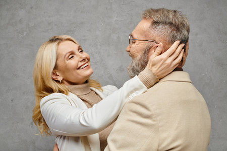 A mature man and woman in elegant attire embrace lovingly against a gray backdrop.の写真素材