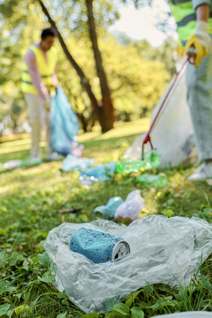 A group of socially active individuals, wearing safety vests and gloves, standing around a field, cleaning up the park together.の写真素材