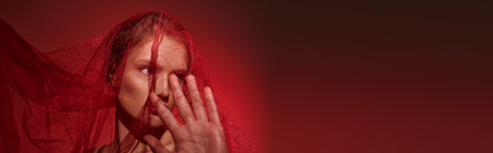 A young woman, embodying classic beauty, covers her face with her hands in a poignant gesture.