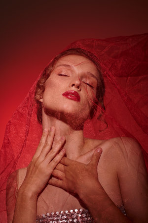 A young woman exudes classic beauty while wearing a veil in a studio setting against a black backdrop.の写真素材
