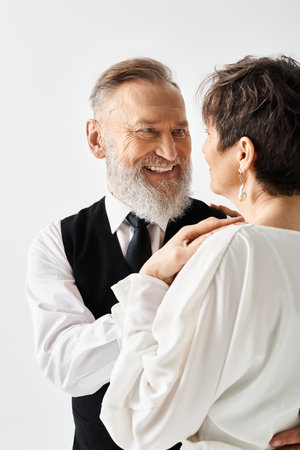 A middle-aged bride and groom in wedding attire standing closely together, celebrating their special day in a studio setting.の写真素材