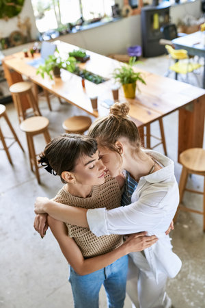 Two women share a warm embrace in a cozy restaurant setting.の写真素材
