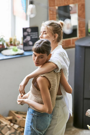 Two women sharing a loving hug in an art studio.の写真素材