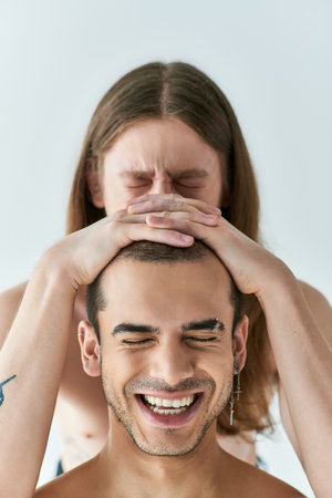 A man with a beaming smile having his boyfriends hands to his head.
