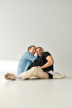 Two men, an appealing and loving gay couple, sitting gracefully on a white floor.の写真素材
