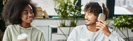 A man and woman, representing cultural diversity, chat while studying together in a modern coworking...