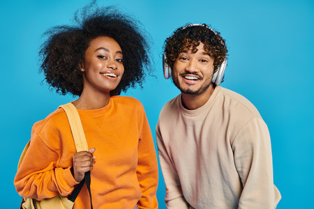 An interracial man and woman stand side by side against a blue backdrop, showcasing unity and...