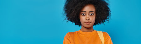 A stylish African American woman in casual attire stands confidently with her voluminous afro hair,...