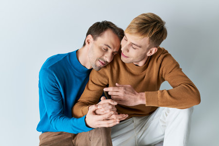 Two men in casual attire sitting together, absorbed in a cell phone.の写真素材