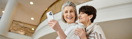 Senior lesbian couple joyfully taking a picture with her cell phone.