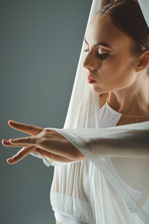 A young ballerina showcases grace and poise in a white dress, extending her hands gracefully.の写真素材