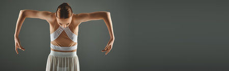 Elegant ballerina poses confidently in a white dress, hands on hips.の写真素材