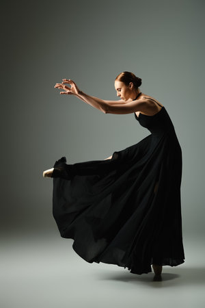 A young, beautiful ballerina in a black dress gracefully dances.の写真素材