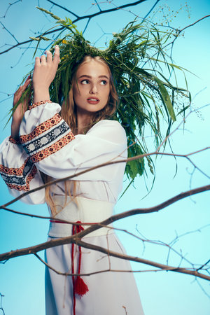 A young mavka in traditional attire stands before a majestic tree, wearing a wreath on her head.の写真素材