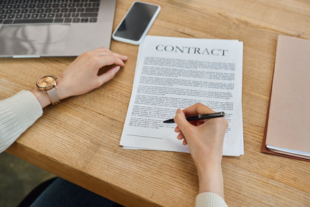 A businesswoman in a modern office sitting at a table, focused on signing a contract related to a franchise concept.の写真素材