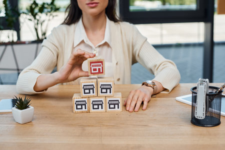 A businesswoman in a modern office sitting at a table with a stack of blocks, engaging in a franchise concept.の写真素材