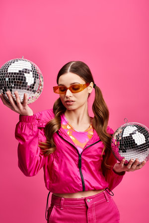 Young woman in her 20s holding two disco balls in front of her face, creating a mesmerizing and...