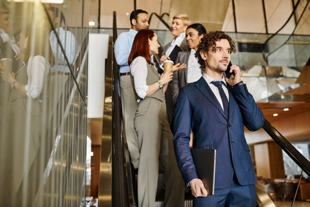 A man in a suit, of an interracial group of business people, talks on a cell phone.の写真素材