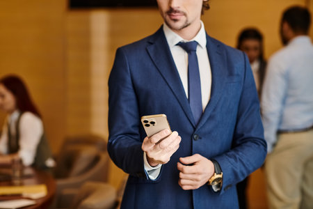 A diverse businessman in a suit confidently holds a cell phone.の写真素材