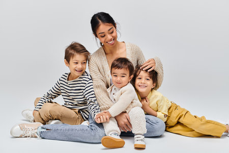 A young Asian mother sitting on the ground with her children, interacting and creating a special...