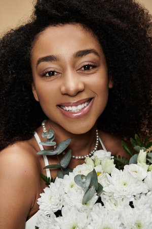 A beautiful African American woman with natural makeup smiles radiantly while holding a bouquet of white flowers.の写真素材