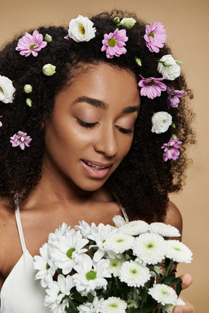 A beautiful African American woman with flowers in her hair, embracing a bouquet of white daisies.