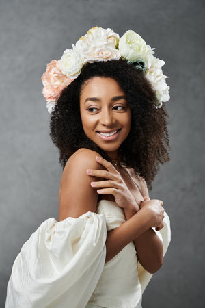 A beautiful African American bride in a white wedding dress smiles and looks over her shoulder, wearing a floral crown.の写真素材