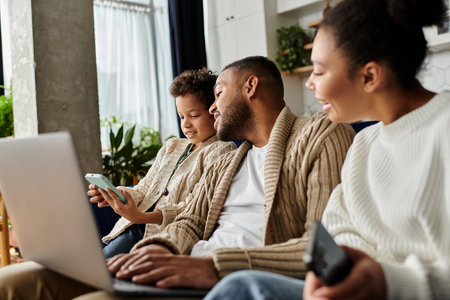 African american family engaged with laptop on couch.の写真素材