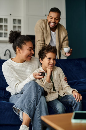 A man and woman, African American, sit together on a blue couch, showing love and togetherness, with...