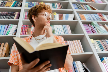 A man absorbed in reading a book in a cozy library setting.