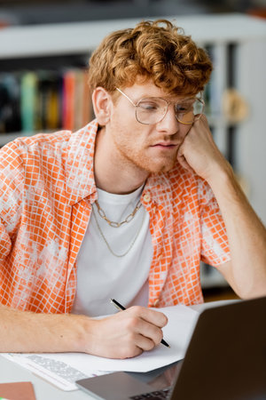 A man engrossed in work on a laptop at a desk.