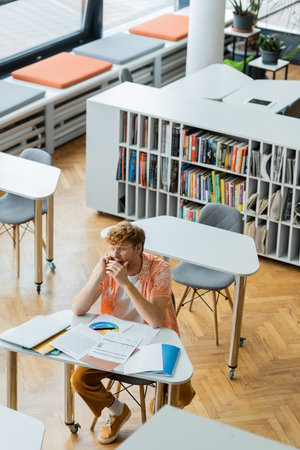 Male student studying intently at library table.