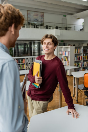 A man stands at a table in a library next to his friend.の写真素材
