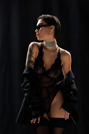 A young woman in lingerie poses confidently, wearing sunglasses and a choker.の写真素材