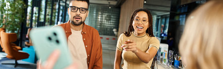 A man and a woman in casual attire stand together in front of a smartphone screen, engaged in a discussion.の写真素材