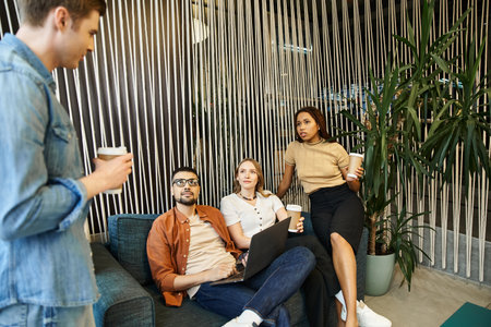 A diverse group of colleagues sitting on a couch in a modern room, engaged in a lively discussion...