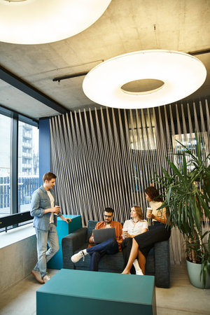 A diverse group of colleagues in a modern coworking space, sitting and engaging in a brainstorming...