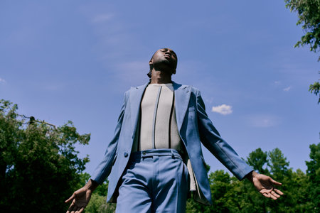 Handsome African American man in a blue suit stands confidently in lush green garden.の写真素材