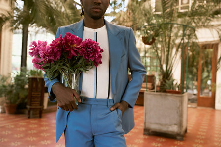 Handsome man in suit holding a bunch of flowers in a vibrant green garden.の写真素材