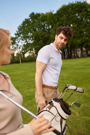 A young couple in elegant attire stands side by side on a golf course, surrounded by lush greenery.の写真素材