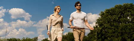 A young couple in elegant clothing walks across a luxurious golf course, enjoying the refined atmosphere.の写真素材