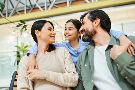 A happy family of parents and kids sit together on a bench, taking a break from shopping in a bustling mall.の写真素材