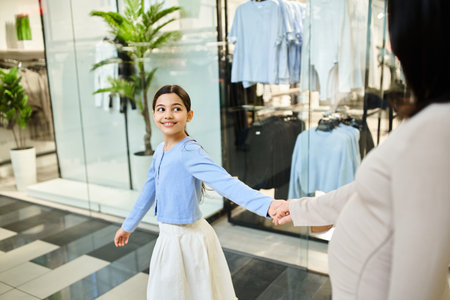 A woman and a young girl happily shop for clothes together in a bustling store.の写真素材