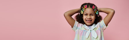 A cute African American girl with colorful hair clips in her hair, wearing a white and pink dress,...