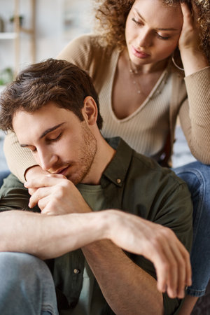 Portrait of man kissing girlfriends hand while hugging each other in bedroom, couple in loveの写真素材