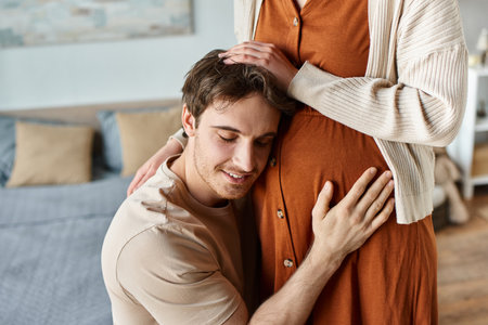 Cropped image of husband listening to baby in pregnant wife belly, hugging parentsの写真素材