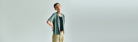 A young queer person confidently poses on a white background in a studio setting.の写真素材