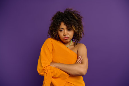 Confident African American woman posing with crossed arms in stylish attire.の写真素材
