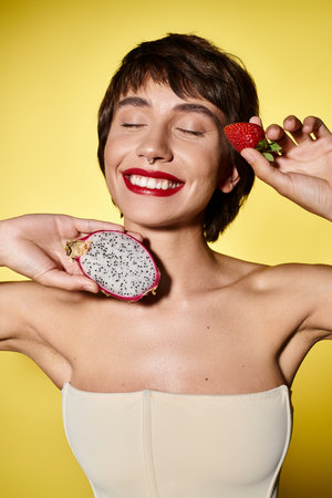 Young woman elegantly holds strawberry and dragon fruit.の写真素材